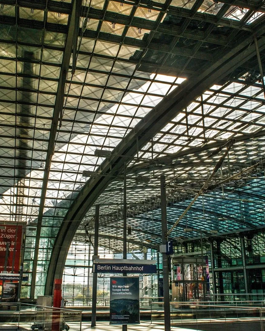 Interior of a modern train station with a massive curved glass and steel roof.